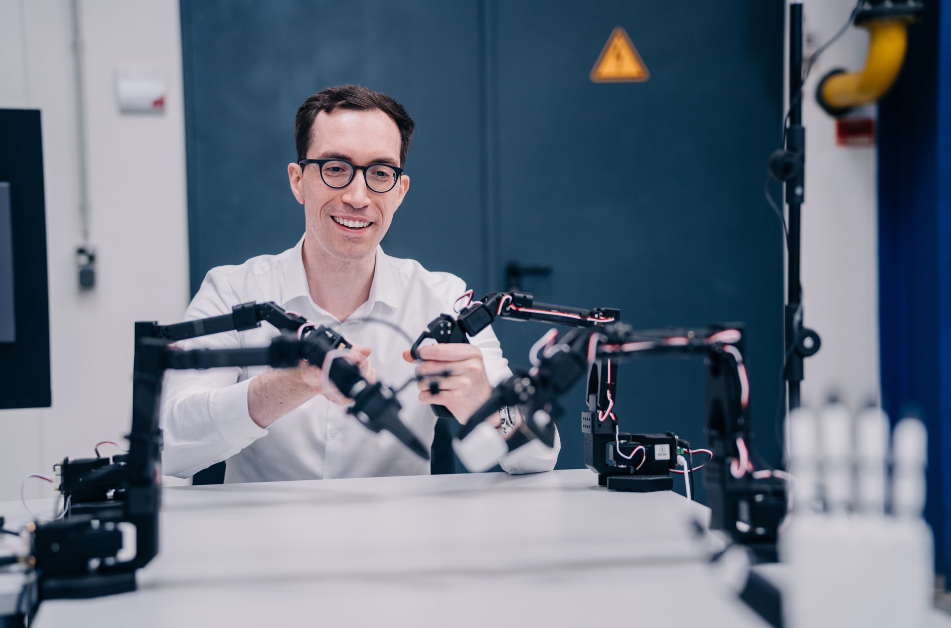 Engineer guiding small robot arms by hand during teleoperation