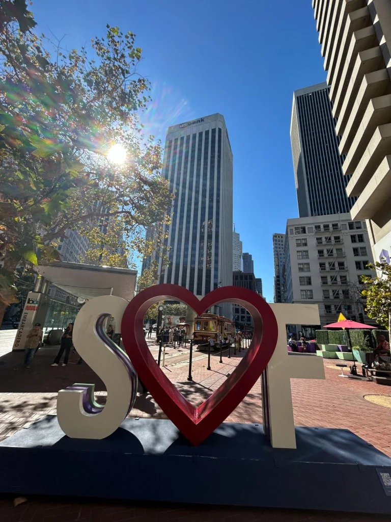 The S♥F sign at Embarcadero, with a cable car on Market Street framed by the heart.